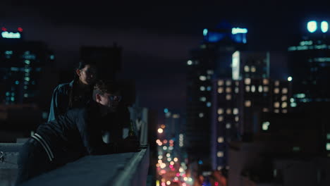 friends hanging out on rooftop at night watching urban nightlife relaxing enjoying vacation weekend