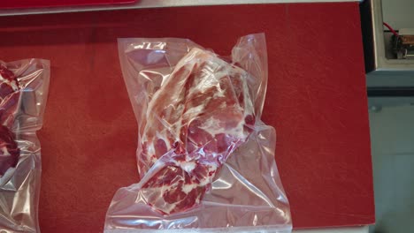 carne envasada al vacío colocada en un banco de trabajo rojo