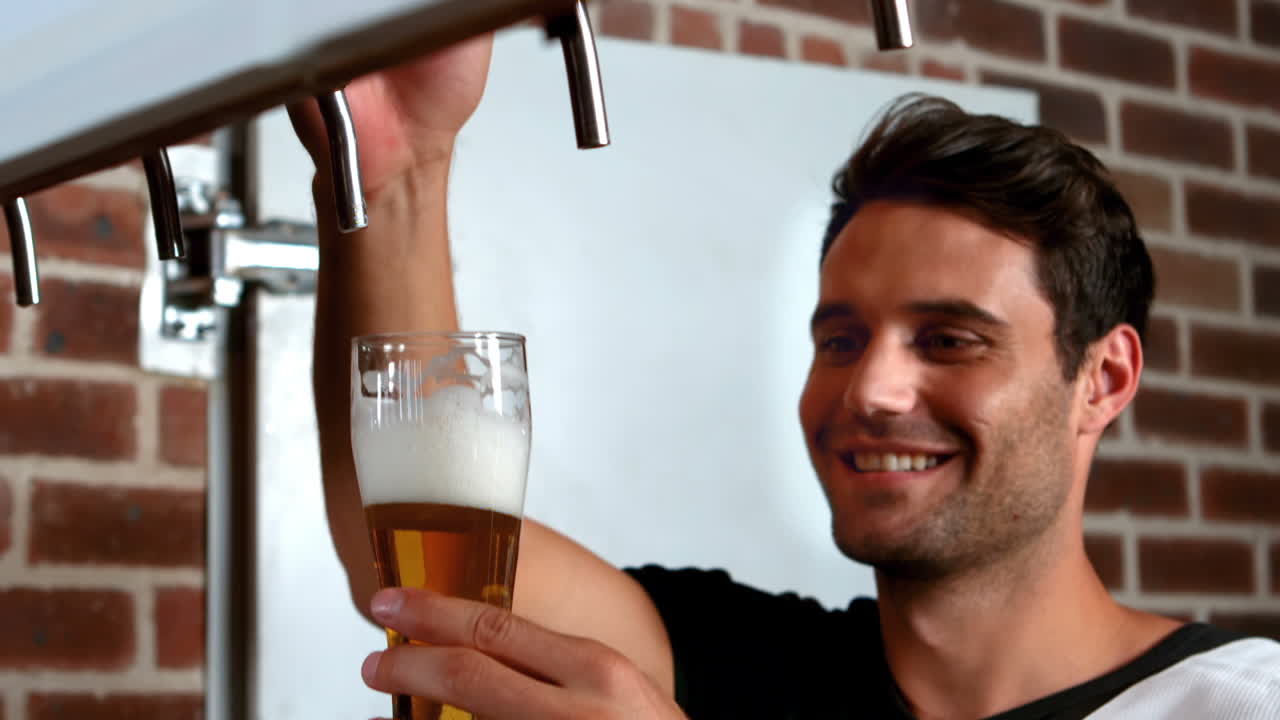 barman sonriente tirando de una pinta de cerveza