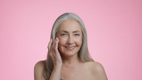 senior woman smiling while applying skincare