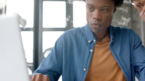 Focused-african-american-casual-businessman-sitting-at-desk-using-laptop-at-home,-slow-motion