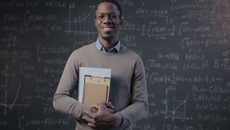 portrait of a smiling teacher in front of a chalkboard filled with math equations