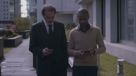 gerentes serios con teléfonos inteligentes hablando y caminando en cámara lenta