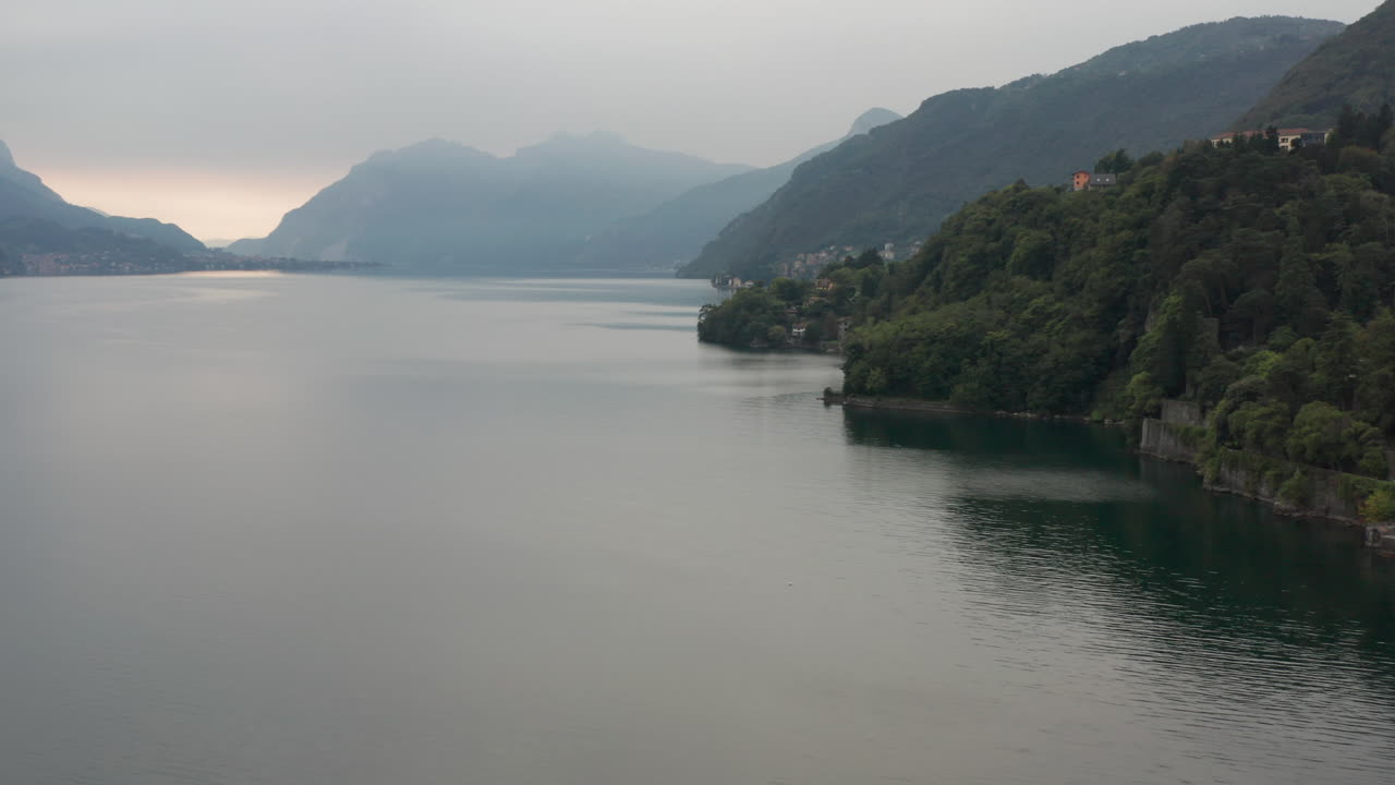 impresionante antena del hermoso lago de como con montañas cubiertas de nubes en el fondo