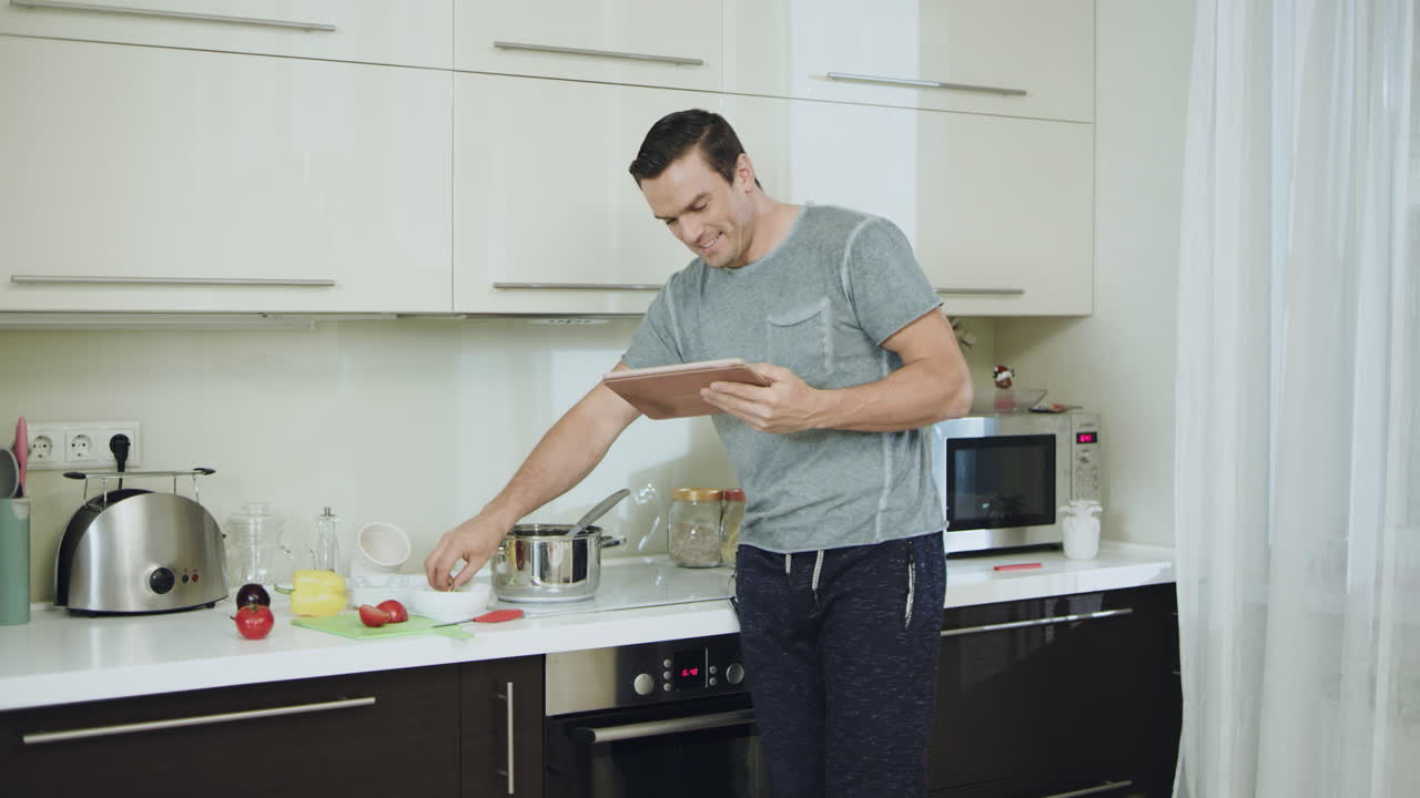 hombre feliz cocinando una cena saludable en la cocina. persona sonriente leyendo la receta
