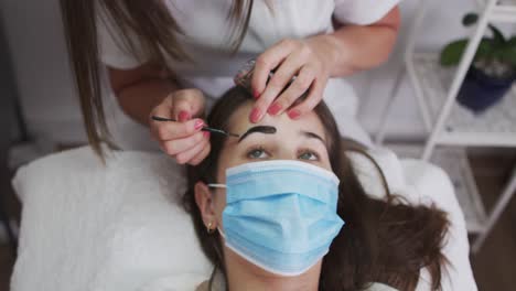 mujer caucásica con máscara de cara acostada con las cejas teñidas