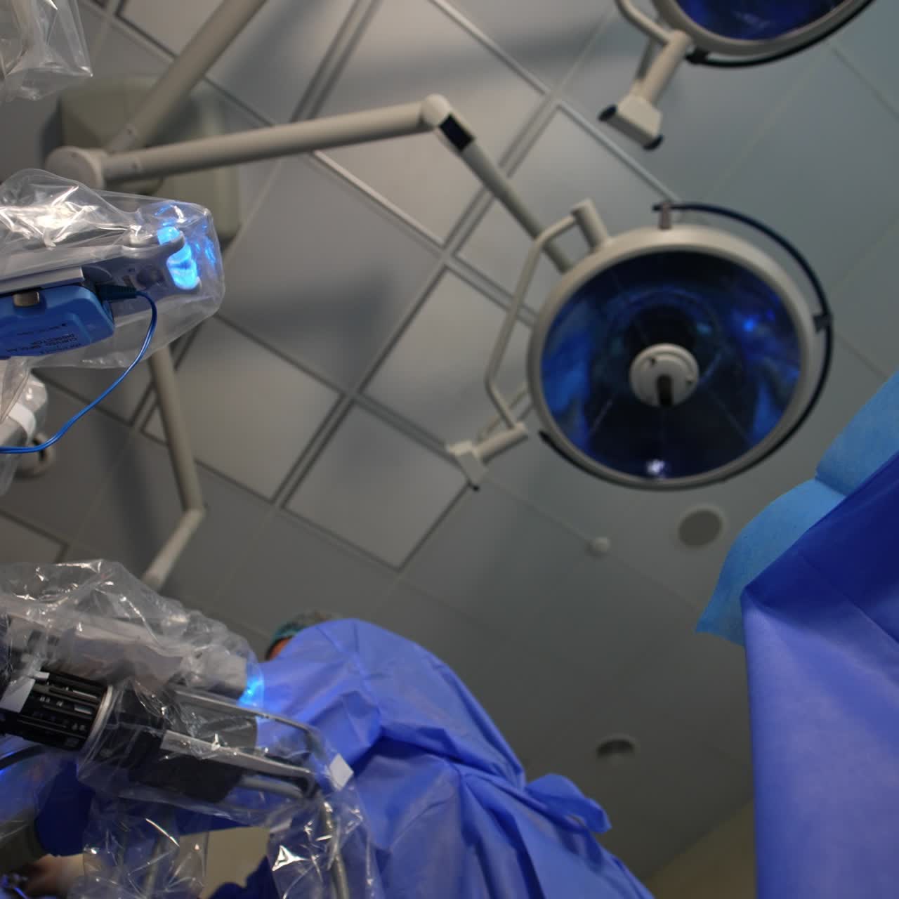 Human doctors cooperating with robotic machine at operation. Surgeons move in the operative field of Da Vinci machine. Low angle view