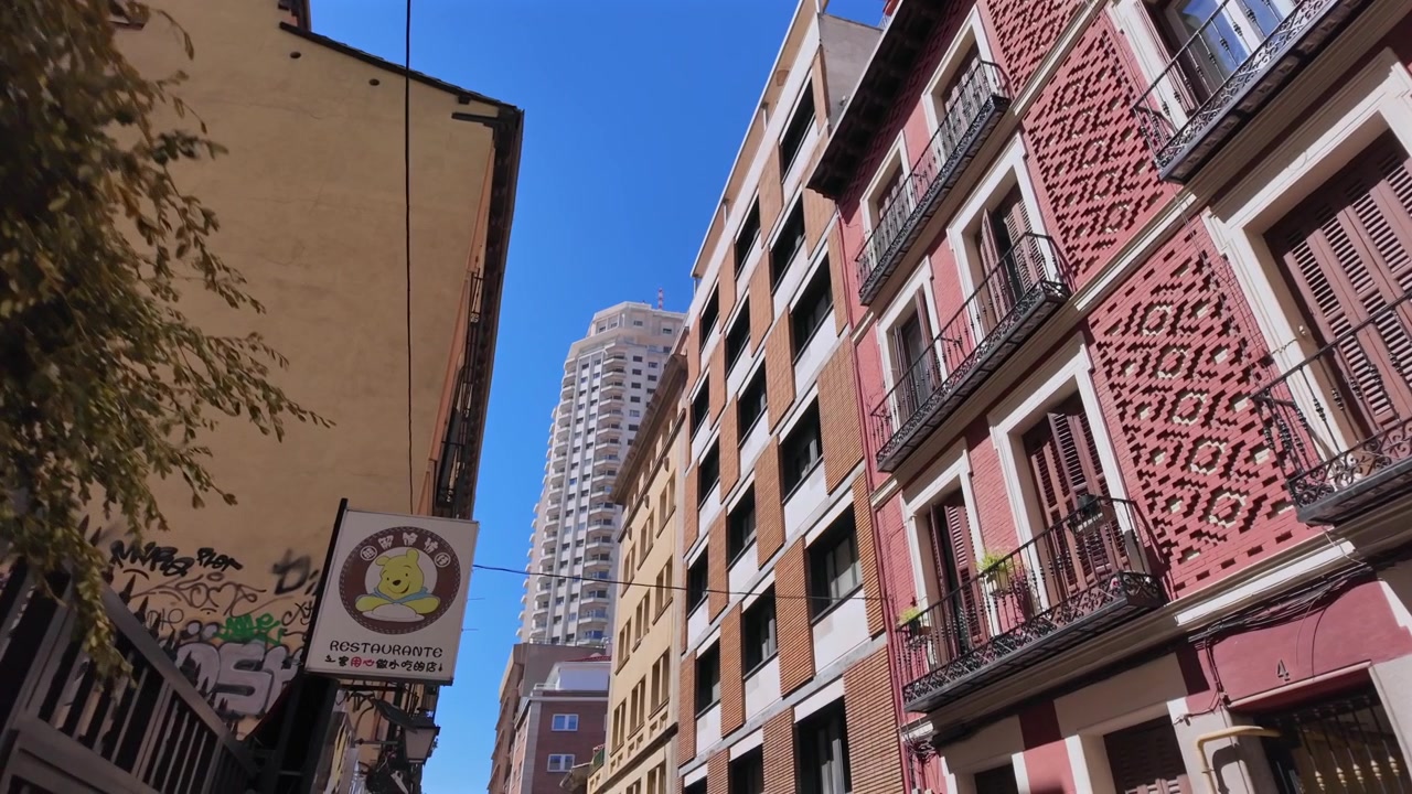 Veduta dal basso di edifici residenziali e architettura stradale stretta a Madrid sotto un cielo azzurro limpido