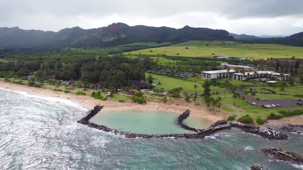 Aerial view of Lydgate Park Pools at Lydgate Beach park near Wailua bay in Kauai with beachfront hotel Hilton Garden Inn Kauai Wailua Bay in background. Holiday in paradise.