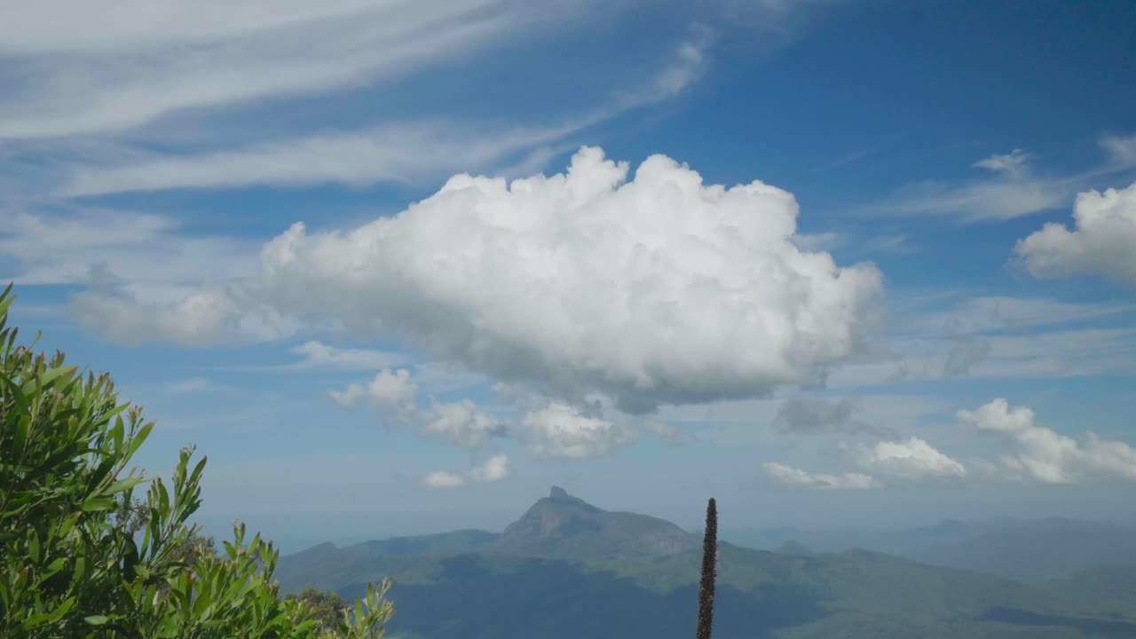 A large cloud floats above a majestic mountain, showcasing the beauty of nature and the sky.