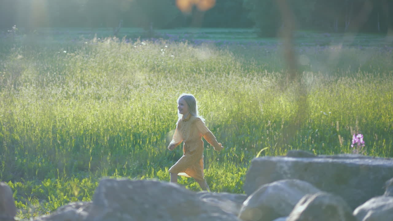 웃고 있는 한 여름 아이가 풀밭을 가로질러 달린다