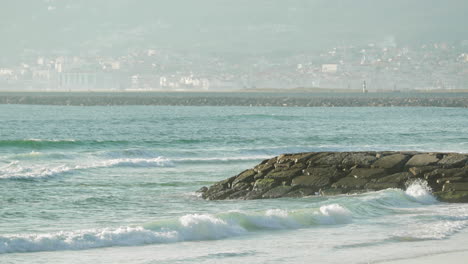 Flutwellen-Gegen-Wellenbrecher-Mit-Nebliger-Stadtlandschaft-In-Figueira-Da-Foz,-Portugal