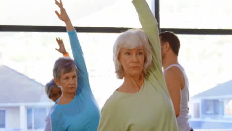 Trainer-assisting-senior-women-in-performing-yoga-4k