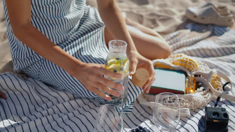 las manos de primer plano preparando un picnic a la luz del sol. chica relajada vierte agua en el vaso