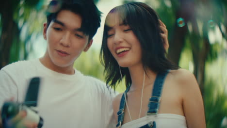 couple singing and making bubbles in a park