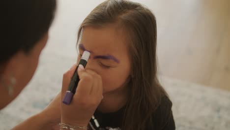 niña pequeña pintando la cara para halloween