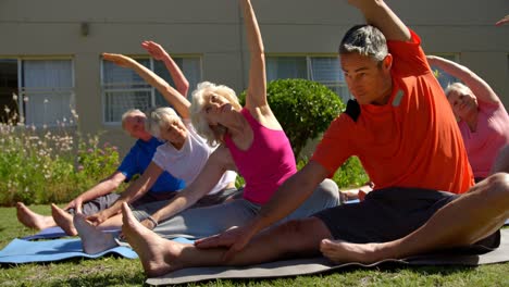 front view of caucasian male trainer training senior people in performing exercise at the garden of