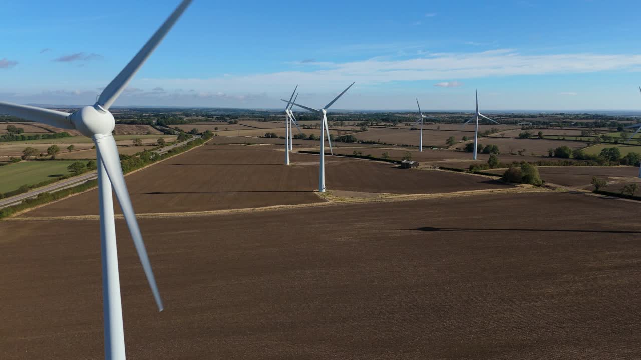 FPV drone flight over wind energy landscape and solar photovoltaic system in rolling hills, England