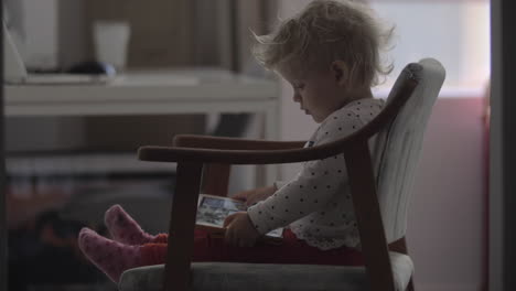 Toddler-girl-watching-cartoons-on-tablet-computer-at-home