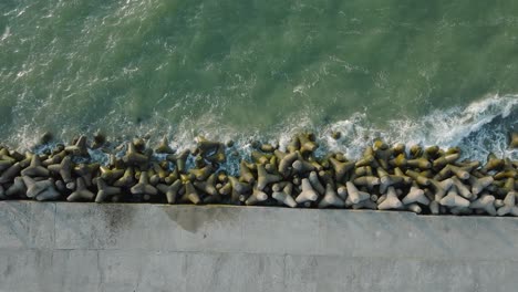 Aerial-establishing-view-of-Port-of-Liepaja-concrete-pier,-Baltic-sea-coastline-,-sunny-day-summer-evening,-golden-hour-light,-big-waves-splashing,-wide-birdseye-drone-dolly-shot-moving-right