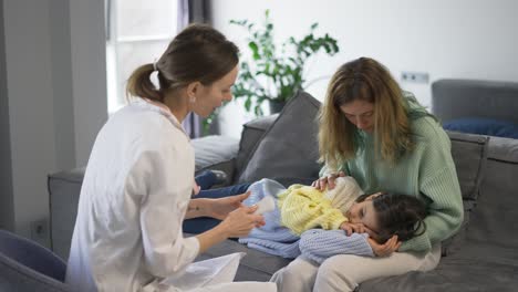 doctor examines baby girl checks temperature on mom's knees