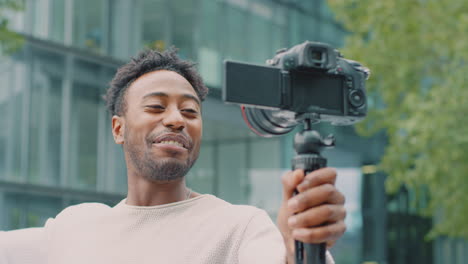 young man travelling through city vlogging to video camera on handheld tripod