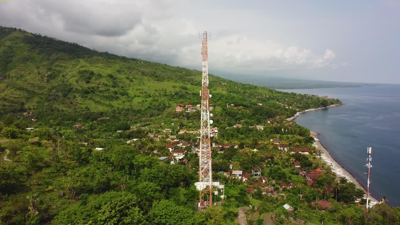 el dron aéreo de la torre de telecomunicaciones 5g gira alrededor del pilón con vista al mar y la montaña verde de la naturaleza salvaje