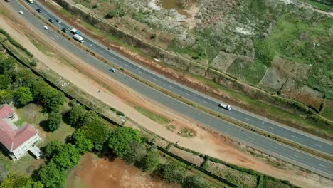 Ascend-aerial-top-down-of-traffic-on-highway-with-cars-and-trucks-surrounded-by-slums-and-dumping-site-with-rotten-water-pools