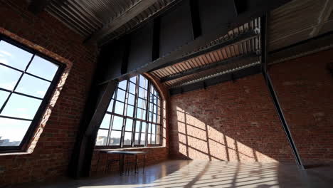 spacious industrial loft with arched window and sunlight shadows