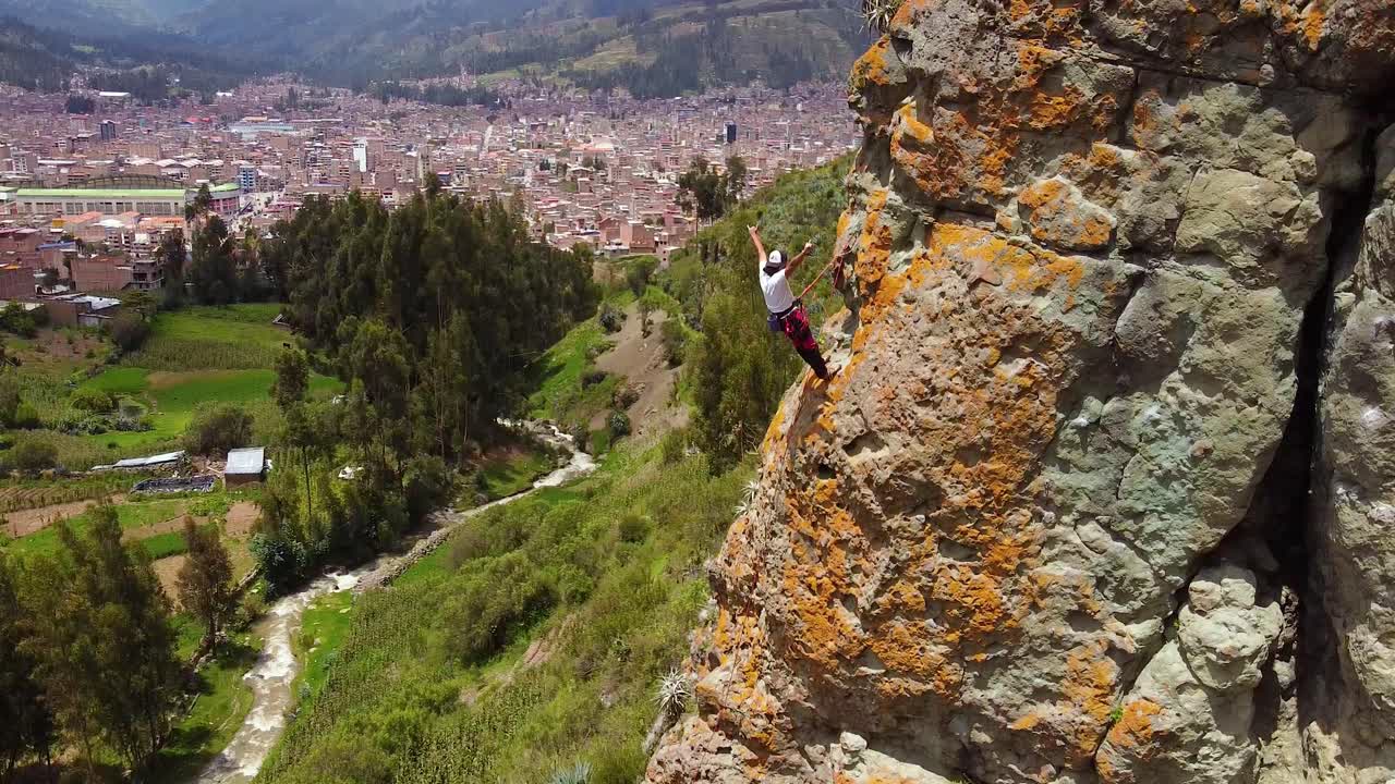 Rock Climber Resting On High Altitude While Climbing Cliff In Huaraz, Peru. aerial tilt-up pullback