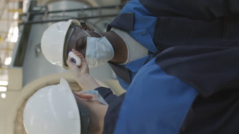 plant supervisor taking workers temperature before workday