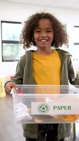 vertical video: in school, child recycling paper in classroom, learning environmental responsibility