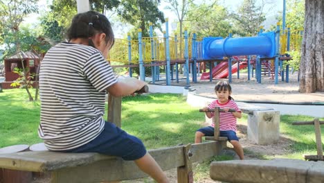 hermanas pequeñas activas jugando en un columpio en el patio de recreo al aire libre. niñas felices sonriendo y riendo en el parque infantil. jugar es aprender en la infancia.