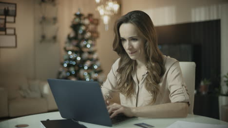 happy woman using laptop computer at xmas home. business woman watching news