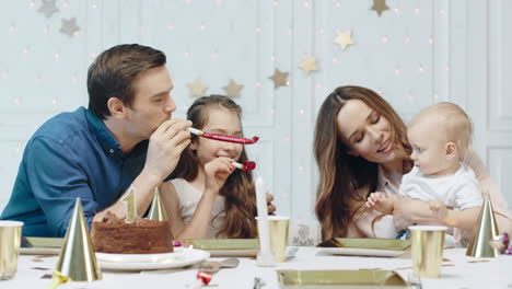 Smiling-couple-with-two-kids-sitting-on-festive-table-in-living-room.