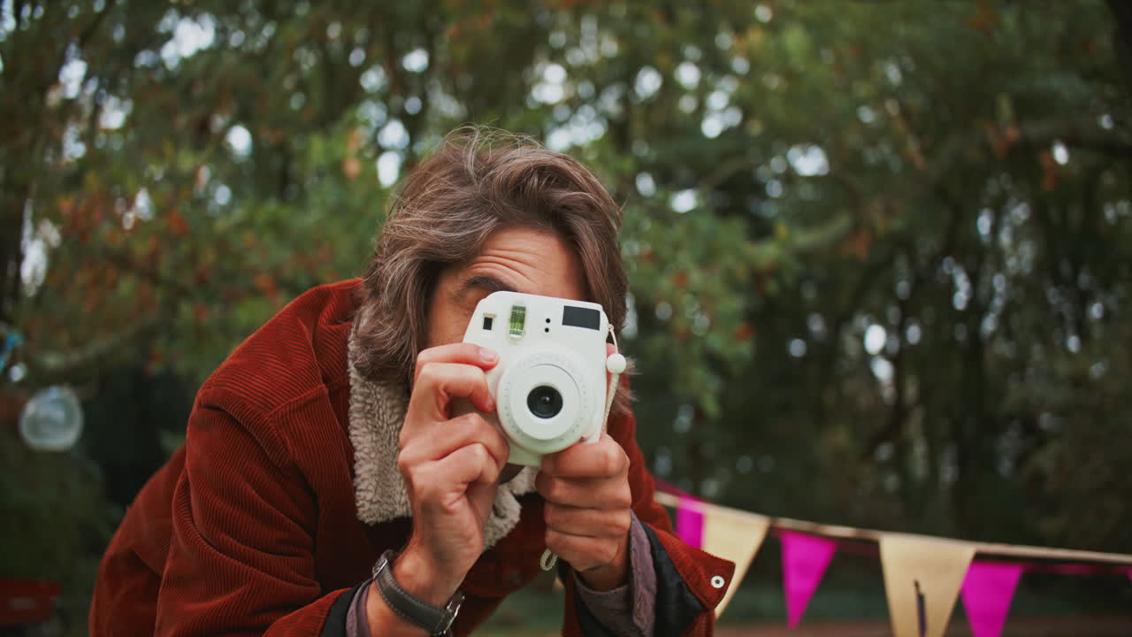 Man taking a picture at a festival with a polaroid camera