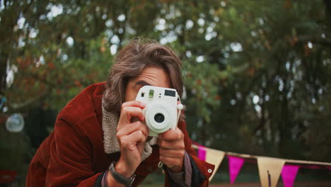 man taking a picture at a festival with a polaroid camera