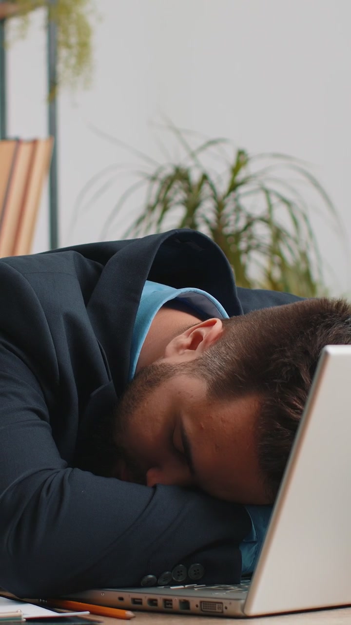 Aburrido, somnoliento, hombre de negocios, trabajador en una computadora portátil, bostezando, quedándose dormido en la oficina de casa.