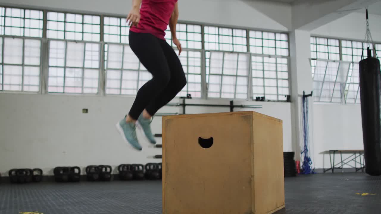 mujer caucásica en forma saltando en la caja de pylo en el gimnasio