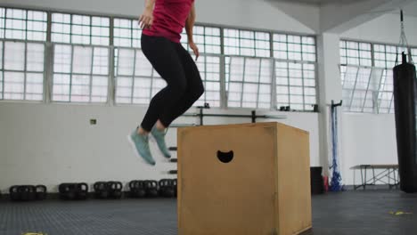 fit caucasian woman jumping on pylo box at the gym