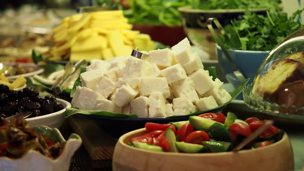 A diverse buffet spread featuring cheese, olives, and fresh salads