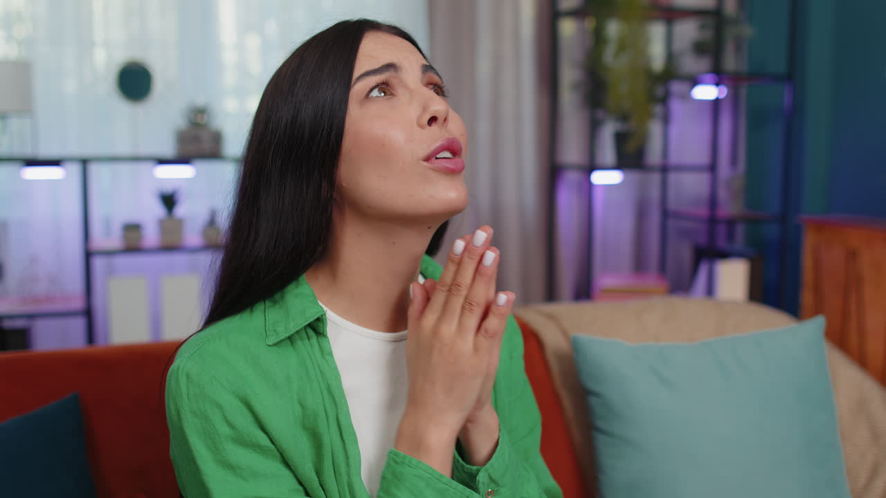 Young woman praying sincerely with folded arms asking God for help, begging apology, making a wish