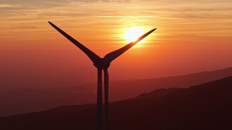 Große Windkraftanlage als Silhouette über Bergen bei Sonnenuntergang