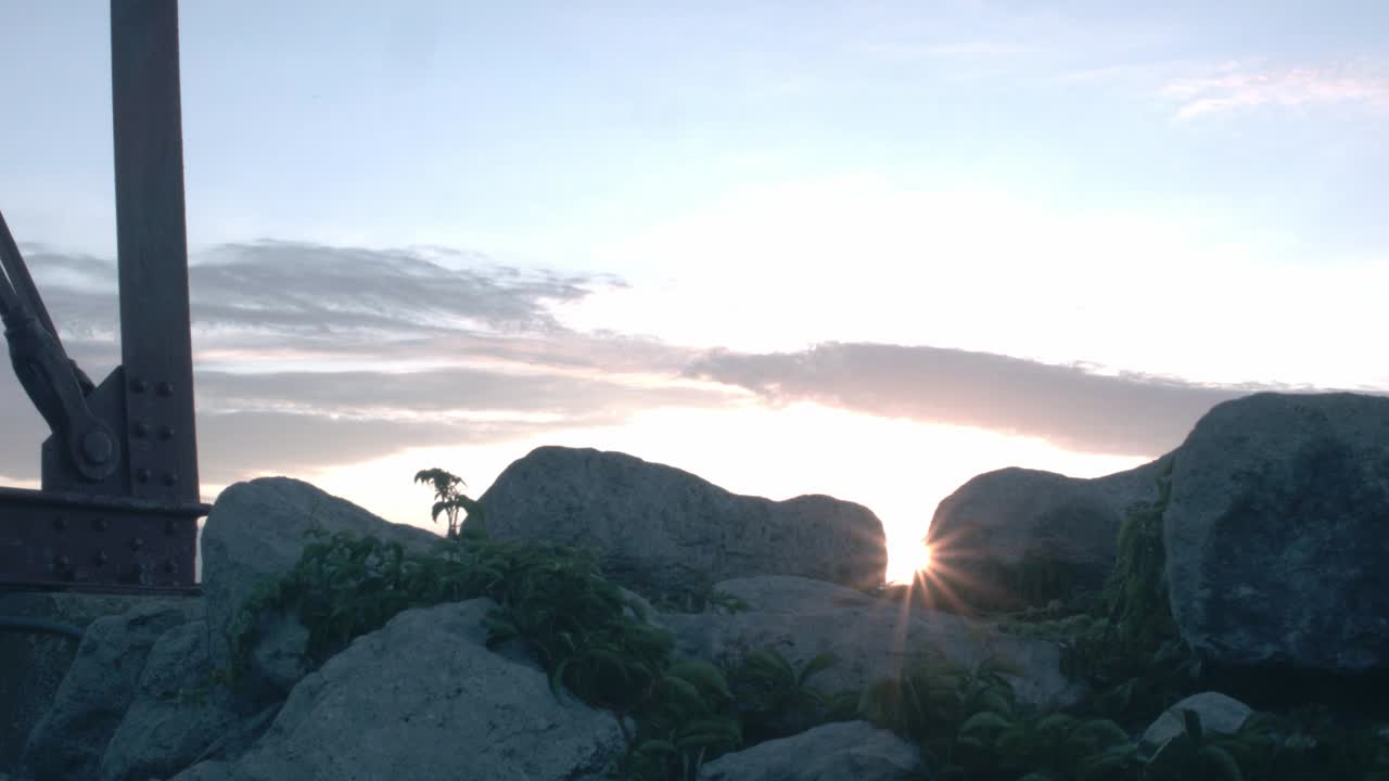 A timelapse with beach rocks in foreground with the arm of a washed up buoy and a cloudy sunrise gives to an incredibly bright sunny morning.