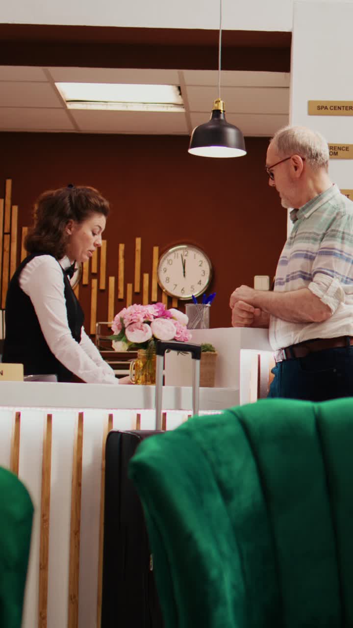 Video verticale: anziano adulto che effettua il check-in nella hall dell'hotel