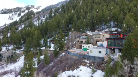 modern luxury estate in hillside during heavy snowfall, aerial ascend view