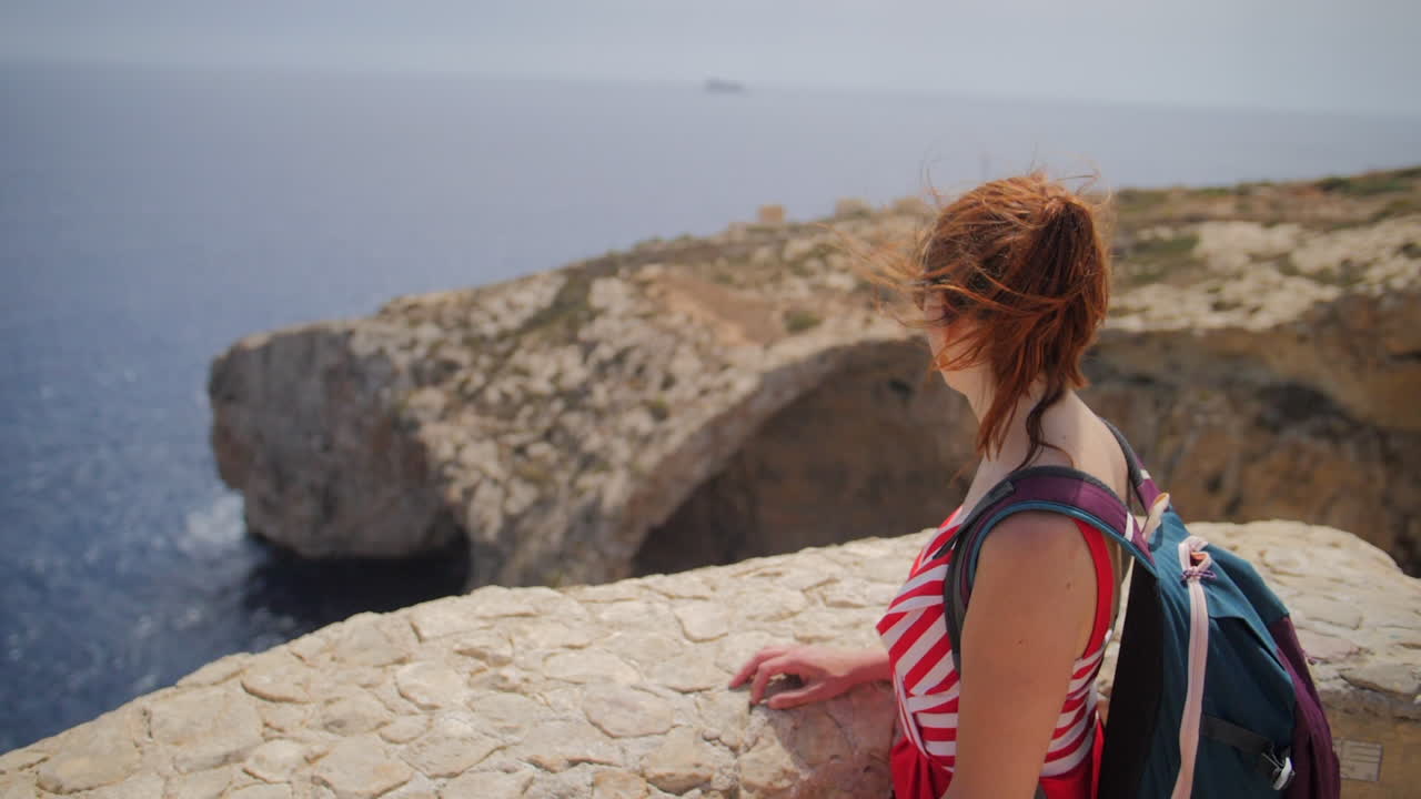 Naispuolinen turisti katsoo Sinisen luolan (Blue Grotto) luolaa näköalapaikalta hidastettuna