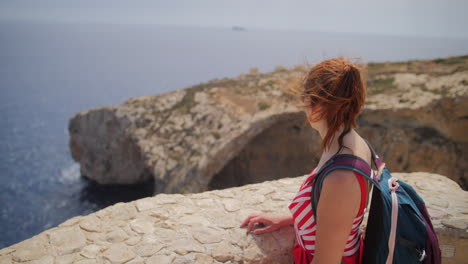 female tourist looking at the blue grotto cavern from a viewpoint in slow motion