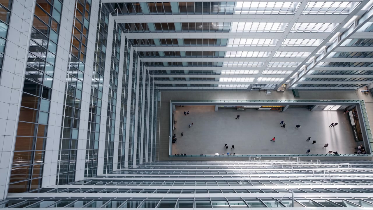 Una toma de gran angular de un interior industrial con vigas metálicas y paneles de vidrio en un espacio amplio, creando una atmósfera neutra con un enfoque en el diseño arquitectónico y la iluminación.