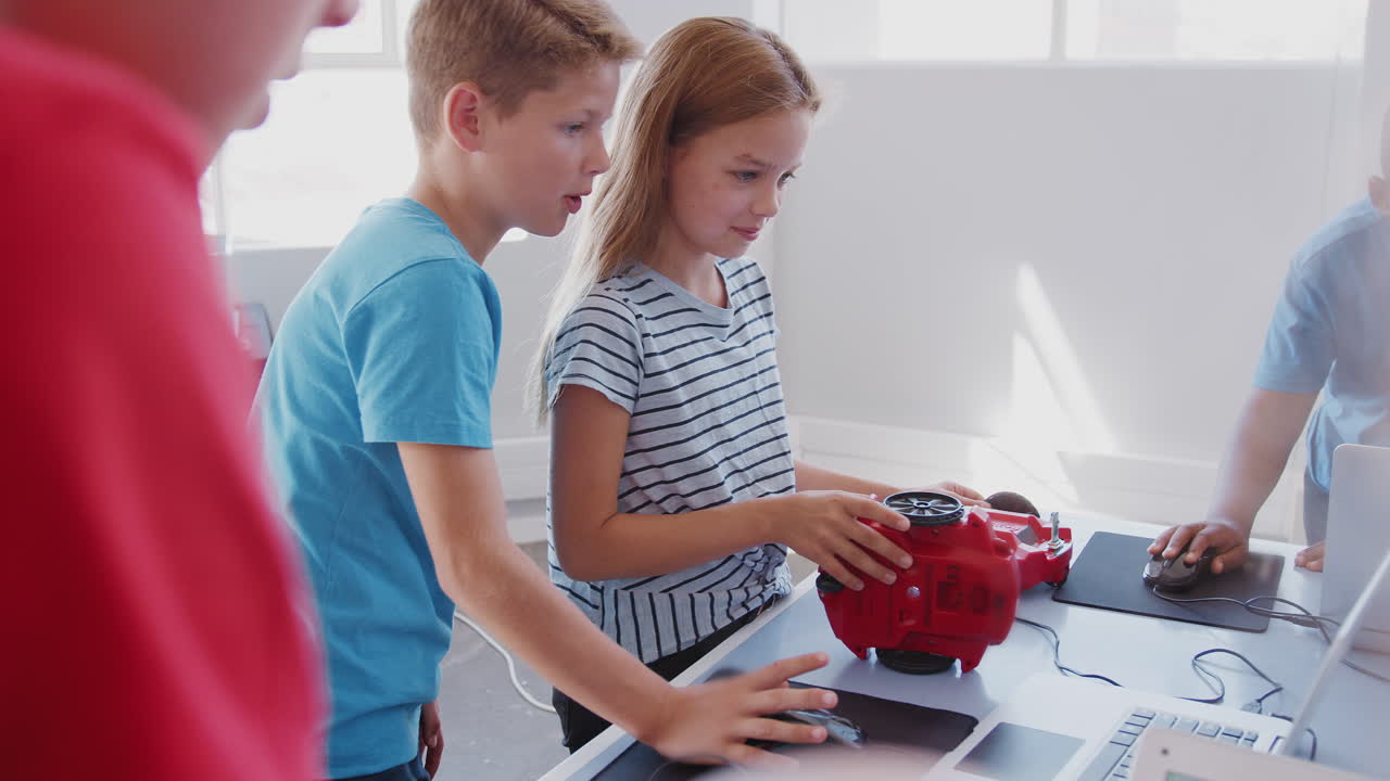 группа студентов в послешкольном классе компьютерного кодирования учится программировать роботное транспортное средство